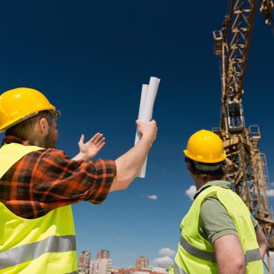 Construction workers signaling to crane operator