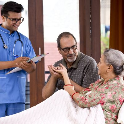 Male nurse making a note of senior patient at home